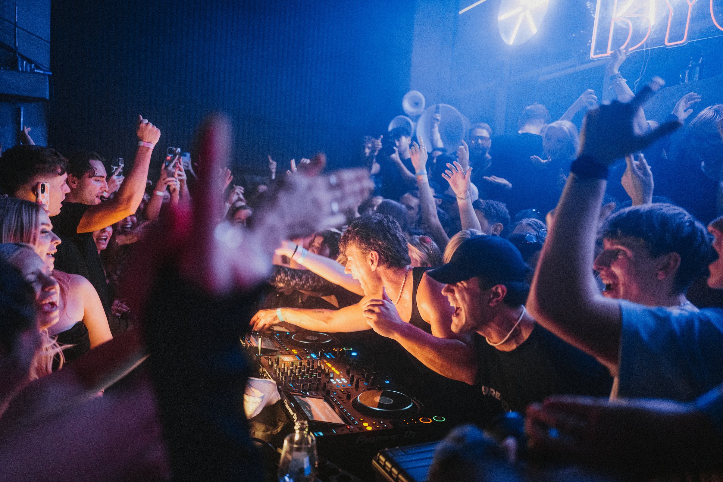 DJ und Publikum bei einer BYOND-Clubnacht in blauem Bühnenlicht